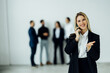 © F8  \ Suport Ukraine - Pretty young business woman standing in the office and using mobile phone in front of team