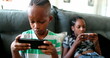 © Marco - Children addicted to technology, kids watching screens at home absorbed in their phones