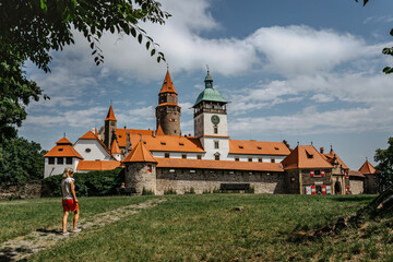 Wall Mural - Girl walking to Bouzov Castle,Czech Republic.Romantic fairytale chateau with eight-storey watchtower built in 14th century.National cultural monument,popular tourist place.Picturesque location