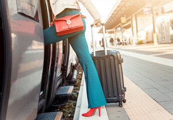 Legs's close up of a business woman getting on the train with bag and trolley bag - Woman on the platform of a train station, taking her train - Travel concept