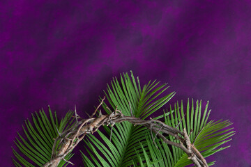 Wall Mural - Partial crown of thorns and palm leaves on a dark purple background with copy space