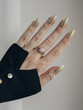 Female hand with glittered golden nails with beautiful stylish rings on fingers.