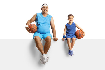 Canvas Print - Mature man in jersey holding a basketball and sitting on a blank panel with a little boy