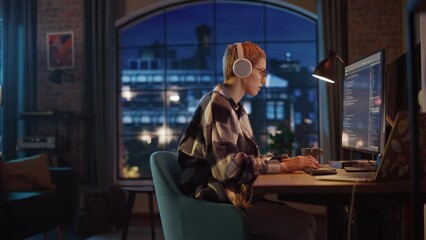 Aufkleber - Young Woman Writing Code on Desktop Computer in Stylish Loft Apartment in the Evening. Creative Female Wearing Headphones, Working from Home on Software Development. Urban City View from Big Window.