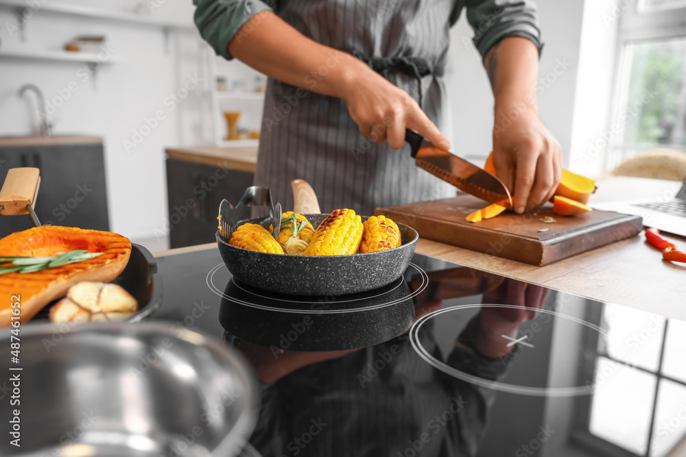 Frying pan with tasty corn on stove in kitchen, closeup