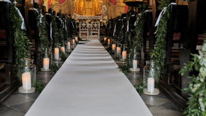 Wall Mural - The beautiful view of the empty church aisle decorated with candles and plants for the wedding ceremony.