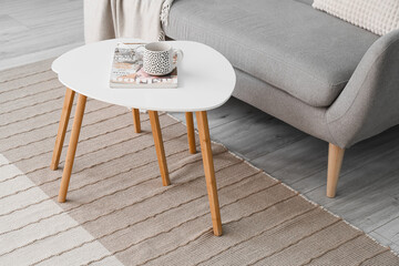 Table with cup, magazine and eyeglasses on new carpet in room