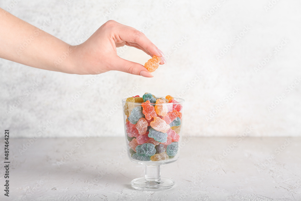 Woman holding jelly bear on light background