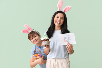 Poster - Little boy, his mother with greeting card, Easter cake and eggs on green background