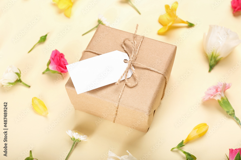 Beautiful spring composition with flowers, blank tag and gift box on yellow background