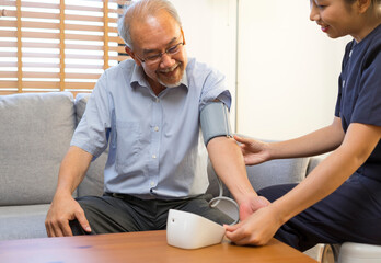 Asian woman nurse at nursing home taking care of senior man. Caregiver Therapist doctor examining an older man use blood pressure gauge.