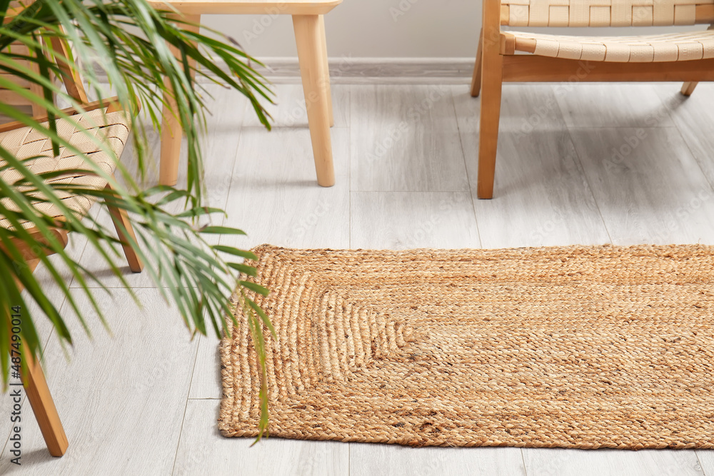 Wicker rug on light wooden floor in room interior