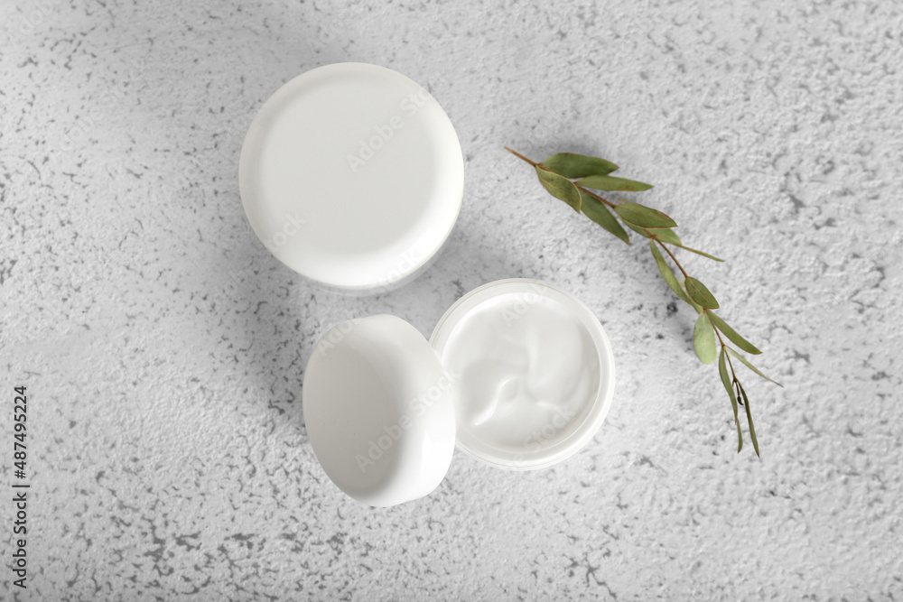 Jars with natural cosmetic cream on light background