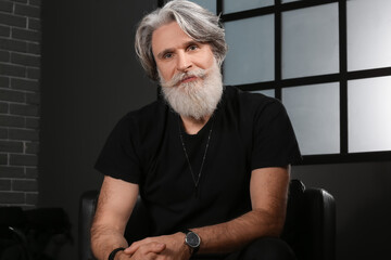 Canvas Print - Portrait of handsome mature bearded man sitting in armchair at home