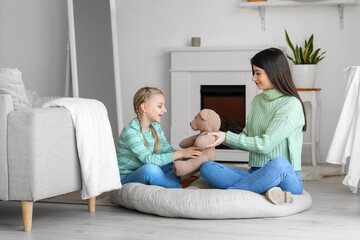 Happy mother giving toy to her little daughter at home