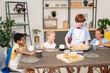 © pressmaster - Happy young kids with raw cookies on tray standing by table in the kitchen in front of camera