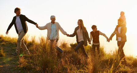 Wall Mural - The hills are alive. Shot of a happy family holding hands on a morning walk together.