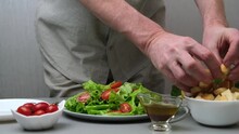 A male chef prepares a healthy and delicious vegetarian Caesar salad. The cook puts croutons in a plate with salad. Close-up. Slow motion. Cooking process. Step by step instruction. Recipe. Step 3.