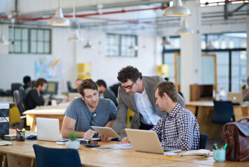 We make technology work for us. Shot of business colleagues discussing matters with the help of wireless technology in their office.