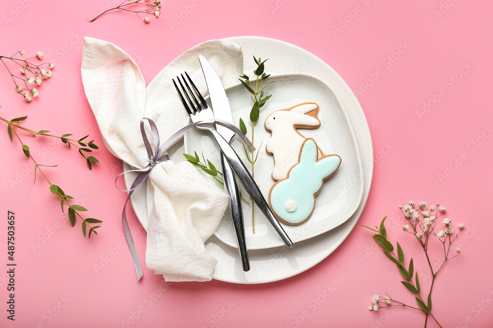 Stylish table setting with Easter cookies on pink background