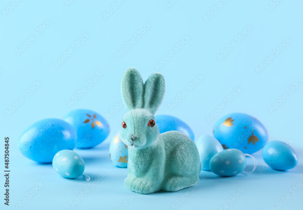 Cute Easter bunny and painted eggs on blue background