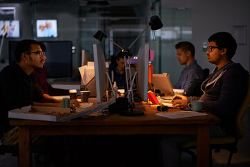 Getting the job done. Cropped shot of a group of young coworkers working in a dimly-lit office.