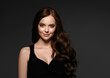 © Utkamandarinka - Beautiful brunette woman in black dress with long beauty curly hair happy clean skin Gray background