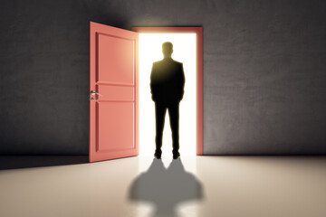 Canvas Print - Successful business man standing in front of bright door in concrete interior with shadow on floor. Future, success and dream concept.