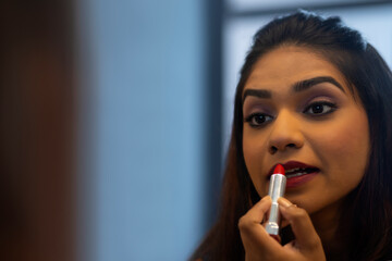 Wall Mural - Close-up portrait of young woman applying red lipstick 