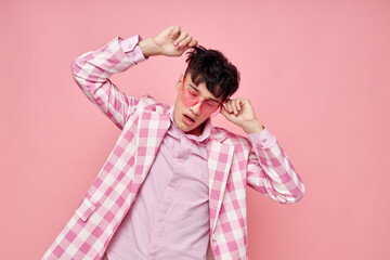 A young man pink glasses checkered jacket fashion posing pink background unaltered