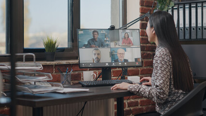 Wall Mural - Employee talking to workmates on online video call, meeting to discuss business project. Woman using remote teleconference on computer with colleagues. Video conference on webcam