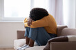 Young black woman with depression crying on sofa at home