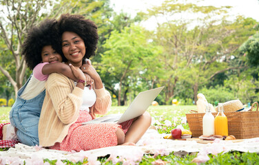 Beautiful mother and daughter doing picnic activities with snacks and bread, fruit juice. They are happy and have bright smiles as they sit in the park. concept of freedom and relaxation