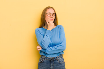 Wall Mural - pretty caucasian woman feeling thoughtful, wondering or imagining ideas, daydreaming and looking up to copy space