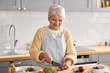 © Syda Productions - healthy eating, food cooking and culinary concept - happy smiling senior woman with knife chopping red onion on kitchen at home