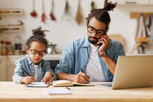 Young African American Dad Working Remotely On Laptop With Child Son At Home