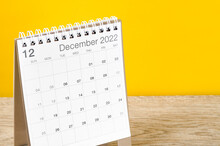 December 2022 Desk Calendar On Wooden Table With Yellow Background.