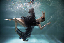 A Woman In A Black Dress Under Water