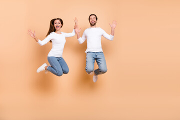 Sticker - Full length body size view of two attractive cheery partners jumping good mood holiday isolated over beige pastel color background