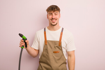 Wall Mural - young cool man looking happy and pleasantly surprised. gardener and hose concept