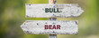 opposite signs on wooden signpost with the text quote bull bear engraved. Web banner format.