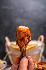 Poster - A vertical closeup shot of a person eating fried chicken legs with sauce