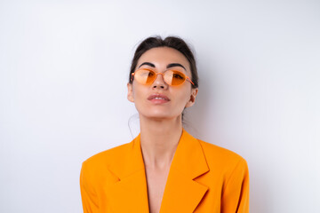 Wall Mural - Young woman in trendy stylish glasses and a bright orange oversized jacket on a white background