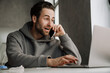 Young beard man talking on cellphone while working with laptop
