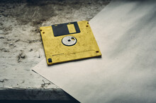 On An Old, Dirty Window Sill With Peeling Paint, There Is An Old Computer Floppy Disk, Covered In Dust, Next To It Is An Old, Dirty Sheet Of Paper, Vintage Still Life