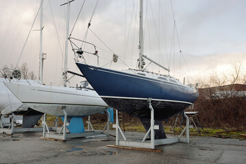 Blue sloop rigged sailboat standing on land in a yacht club. Service, repair, transportation, sport, recreation, leisure activity