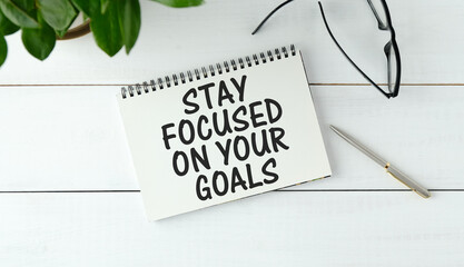 Inspirational quote - Stay focused on your goals. With text message on white paper book, pen, a cup of morning coffee.