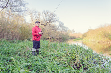 Wall Mural - Angler athlete casts spinning rod into the river.