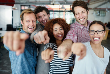 Poster - Our team wants you. Portrait of a group of smiling coworkers pointing at the camera while standing in an office.