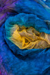 Vertical photo of fabric dyed in different colors and laid out in an abstract form, to be used as a backdrop